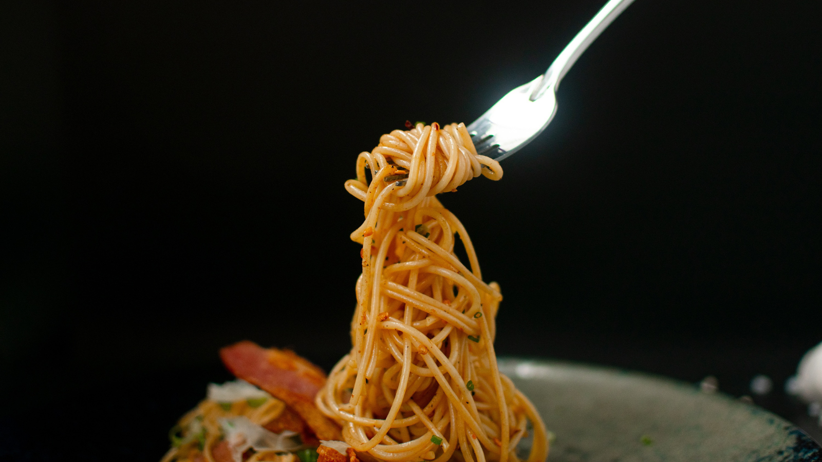 spaghetti twisted on a fork with a black background