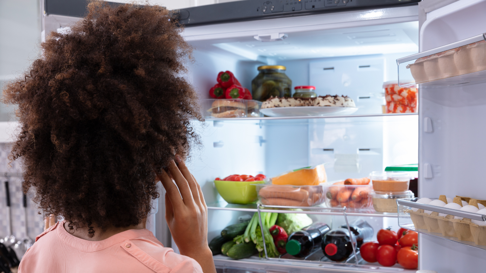 close up of a woman looking into a refrigerator